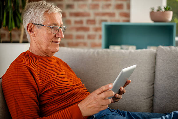 istock Senior man enjoying leisure time at home while using a tablet in a relaxed living room setting 2239734700