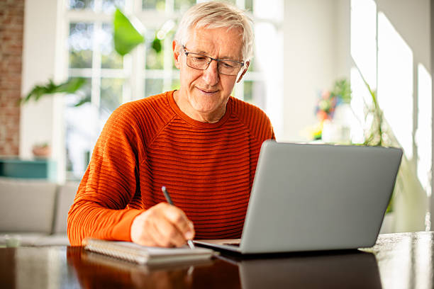 istock Senior man enjoying productive time in home office while writing and working on laptop 2239735064