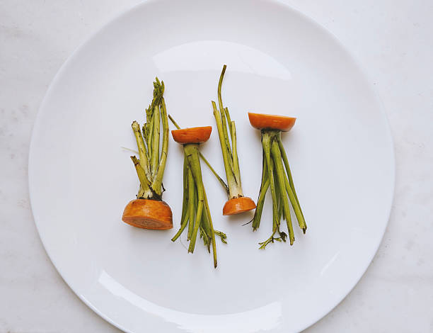 Carrot tops, on a white plate. Light background. Environmentally responsible behavior, ecological, recycling waste concept. Zero waste. sustainable consumption and conscious consumption. part of the series.