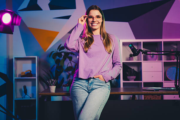 istock Young Woman In Casual Attire Hosting a Virtual Podcast in a Neon-Lit Studio Setting with Professional Equipment 2239743584