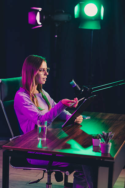 istock Video chat blogger podcasting in a studio with colorful lighting, utilizing a microphone setup and tablet for media content creation 2239743612