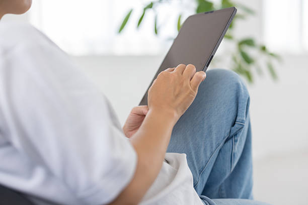 istock Woman using tablet on sofa in bright white living room 2239745008