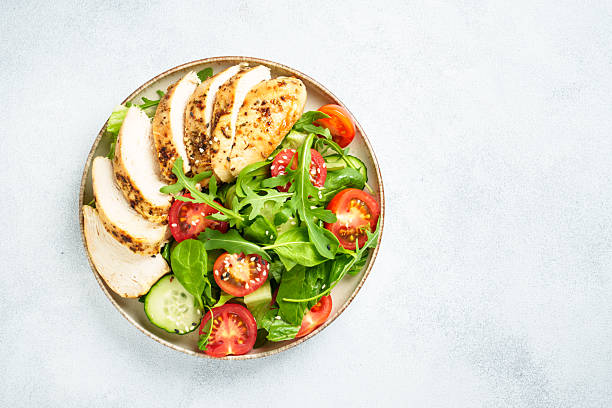 istock Green salad with grilled chicken meat at black table. 2239746659