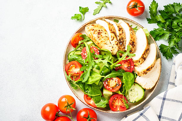 istock Green salad with grilled chicken meat at black table. 2239746663