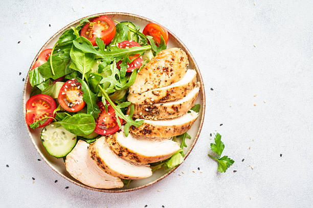 istock Green salad with grilled chicken meat at black table. 2239746675