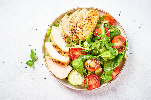 istock Green salad with grilled chicken meat at black table. 2239746676