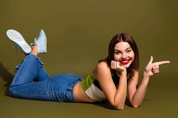 istock Young woman in casual attire smiling and gesturing on a khaki backdrop, emphasizing positivity and modern fashion 2239748173