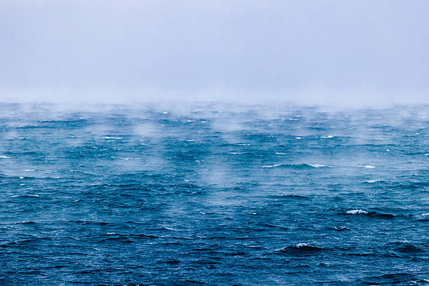 Aegean Sea, Greece – 2 October 2025: Atmospheric view of the sea covered by evaporation fog, also known as sea smoke, caused by cold winter air passing over warmer water. The deep blue waves and soft mist create a minimalist natural abstraction, symbolizing cold weather, climate change, and the raw power of the sea.