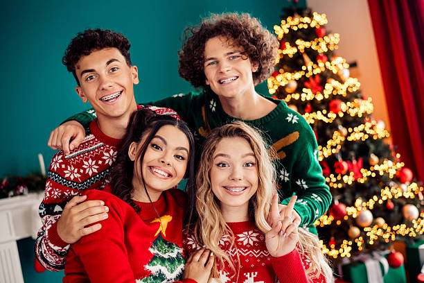 istock Joyful friends celebrating Christmas around a festive tree adorned with glowing lights, wearing cozy sweaters and sharing festive cheer indoors. 2239749358