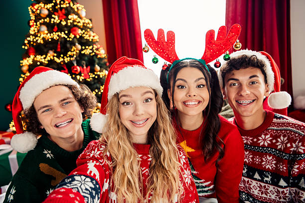 istock Cheerful teens in festive sweaters sharing a joyful Christmas moment by the decorated tree indoors 2239749556