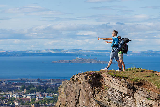 istock Two hikers marvel at expansive views from a grassy cliff edge 2239751380