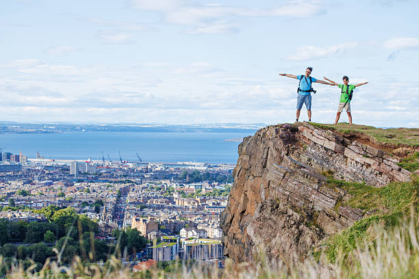 istock Dad with kid enjoys scenic cliff view, arms wide open in delight 2239751396