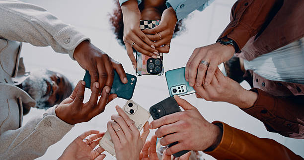 istock Business people, hands and below with phone in circle for data sync, share or communication in office. Low angle, group or employees with mobile smartphone for networking or connectivity together 2239752540