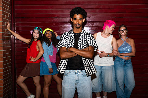 Multiethnic group of young friends having fun on the stretts in the night - Stylish cool multiracial people wearing stylish clothing hanging out before party in a disco club