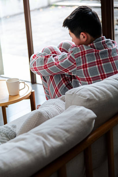 istock Sad teenage boy sitting on sofa at home 2239755708