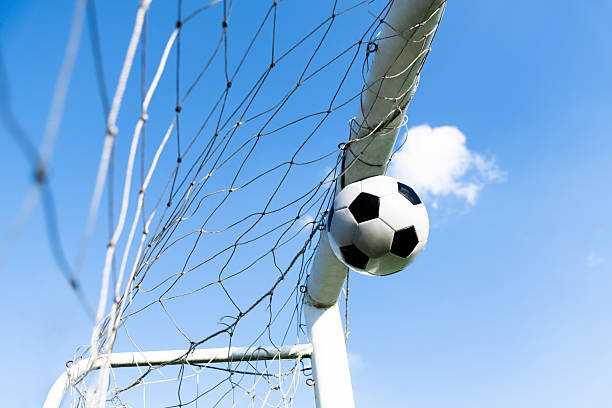 istock Soccer ball hitting the net against blue sky 2239755857