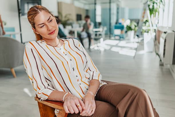 istock Young woman relaxing in modern office while colleagues collaborate in background 2239759662