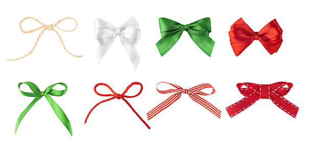 Assorted collection of festive ribbon bows in red, green, white, and natural tones made of satin, fabric, and jute twine, isolated on white background.