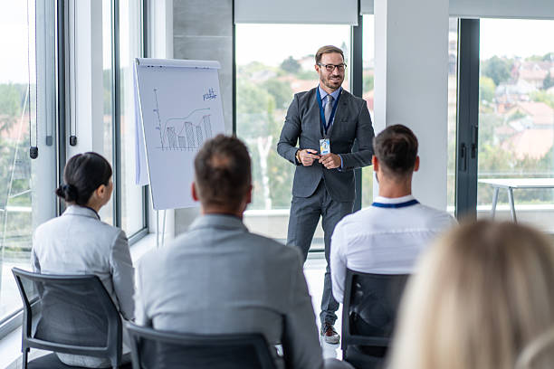 istock Motivational Business Speaker Engaging with Attentive Crowd 2239760653