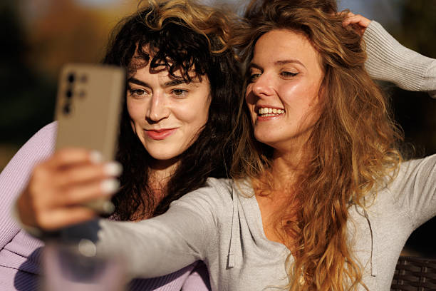 istock Friends enjoying a sunny day together while taking selfies outdoors in a lively park setting during early afternoon 2239760674