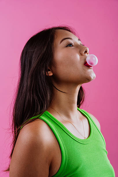 istock Young woman blowing pink bubble gum up 2239764947