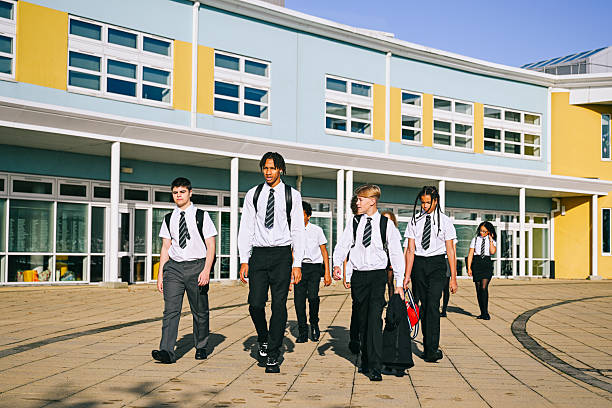 istock High school boys wearing uniform walking past modern school building 2239765285