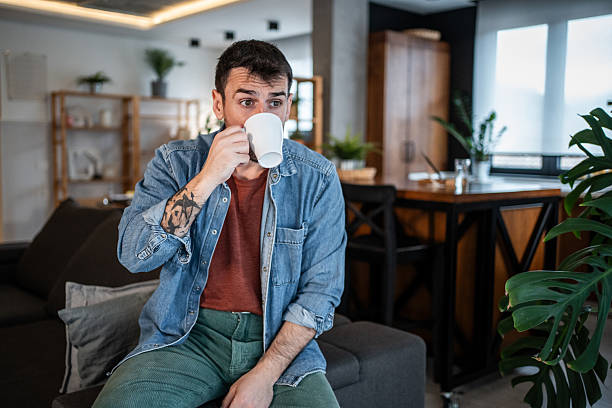istock Casual man drinking coffee on sofa receiving unexpected news 2239766134