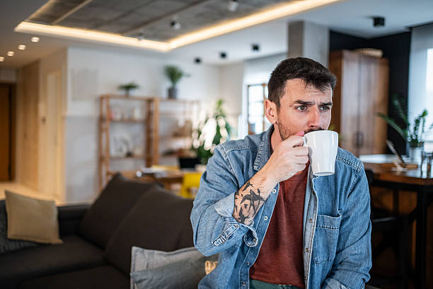 Young man contemplating while drinking coffee at home