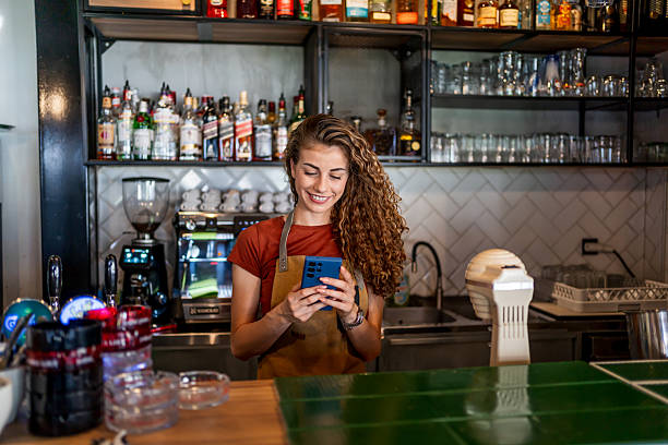 istock Barista woman smiling and using smartphone in a cafe 2239766504