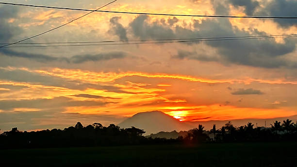 istock Breathtaking evening sky filled with colorful clouds during a beautiful sunset over a silhouetted mountain and trees 2239766754