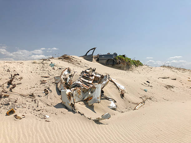istock Old vehicle carcass atop bright sand dunes in a desert-like setting. Visible environmental impact in the natural scenery. 2239768555