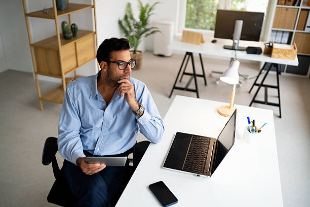 istock Business professional reviewing information on a laptop while holding a tablet in a modern office 2239768907
