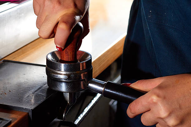 istock Barista using a tamper to press ground coffee into a portafilter 2239768936
