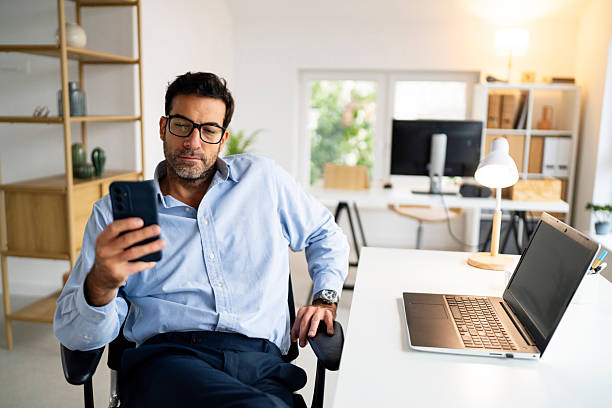 istock Business professional taking a break and checking his smartphone at the desk 2239769288
