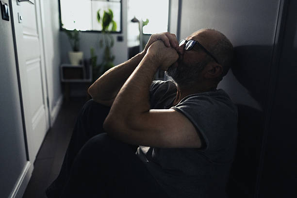 istock Silhouette of a Sad Man Sitting Alone in a Dark Hallway 2239769852
