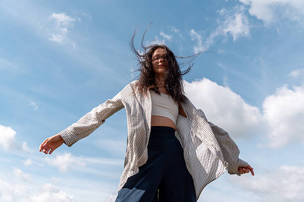 istock Low angle view with young woman enjoying the wind on a sunny day 2239772110