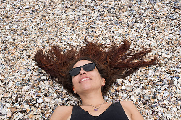 Young woman lying on the beach of Cabo Polonio with her long hair spread over shells