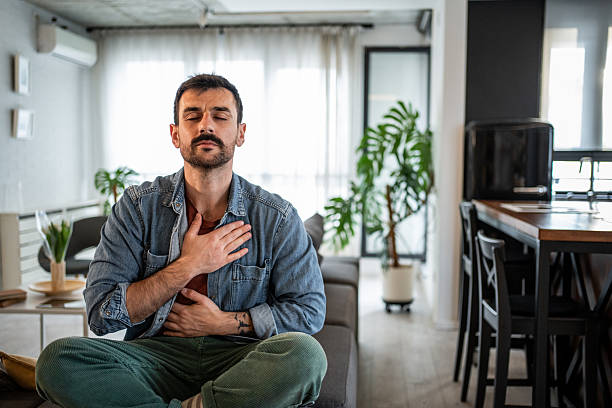 istock Man practicing mindful meditation with hands on chest at home 2239772563
