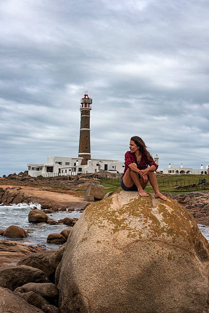 Woman sitting on a rock at the edge of the sea in Cabo Polonio on the coast of Uruguay