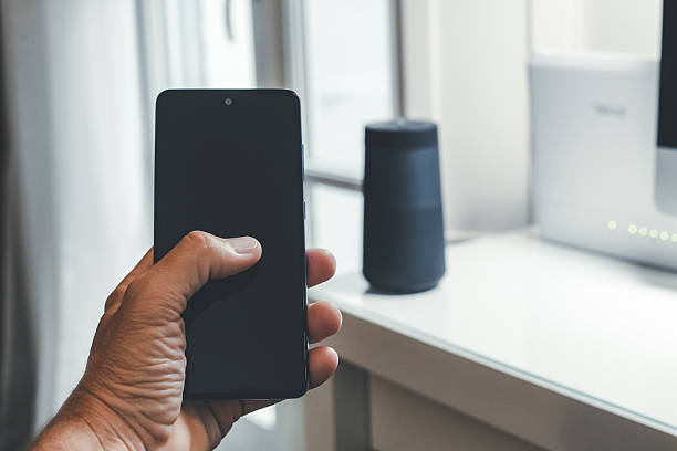 istock Smartphone in hand. Speaker, router, computer on desk. Technology, domotics, home automation concept 2239781799
