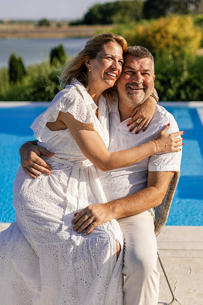 istock Mature married couple sitting by the pool and hugging 2239783441