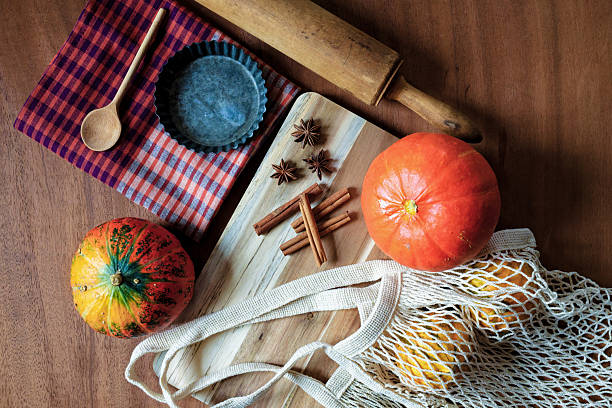 Two pumpkins, cinnamon sticks, star anise and other baking tools are arranged on a wooden table to prepare delicious pumpkin pie for the Autumn holiday. The process of baking can bring joy, when family gather to enjoy Thanksgiving treats. Copy space for text, directly above - Thanksgiving, food and drink