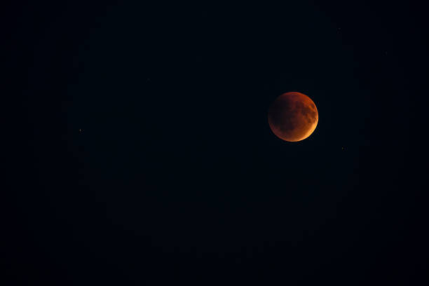 Blood red moon in night sky. Celestial prophecy. Lunar eclipse in dramatic red color with a cosmic sparkle. A symbol of transformation.