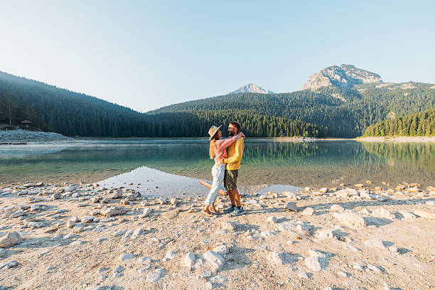 istock Couple Embracing by Mountain Lake Shore 2239786347