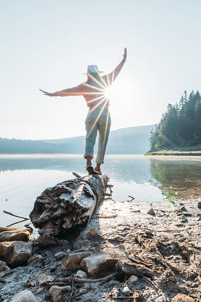 istock Woman Balancing on Log by Calm Lake 2239786415