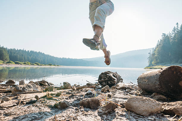 istock Person Jumping Over Rocks by Lakeside Forest 2239786464
