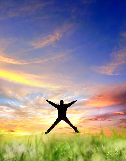 One young man jumping on green landscape during sunset