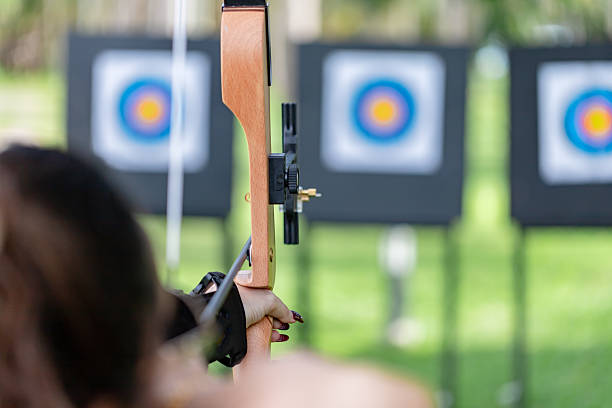 istock Archery Focus: Close-up of Archer Aiming Recurve Bow at Target on the Range 2239790135