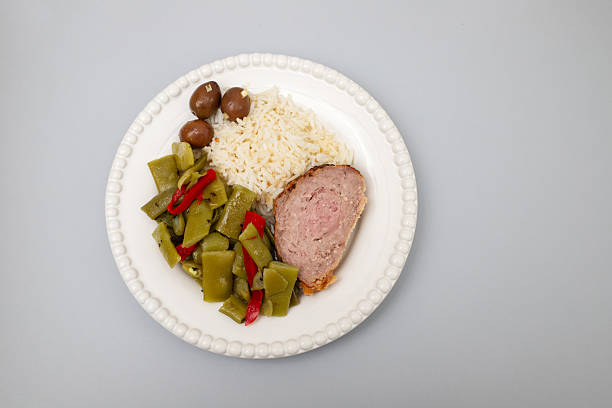 Meat rolls stuffed with ham with boiled rice and olives on plate