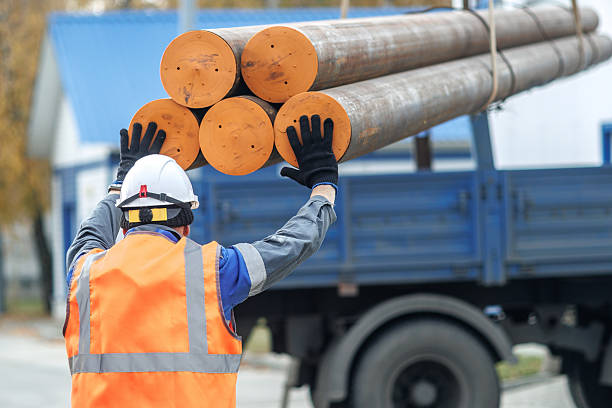 Construction Worker Loading Wooden Poles onto Truck